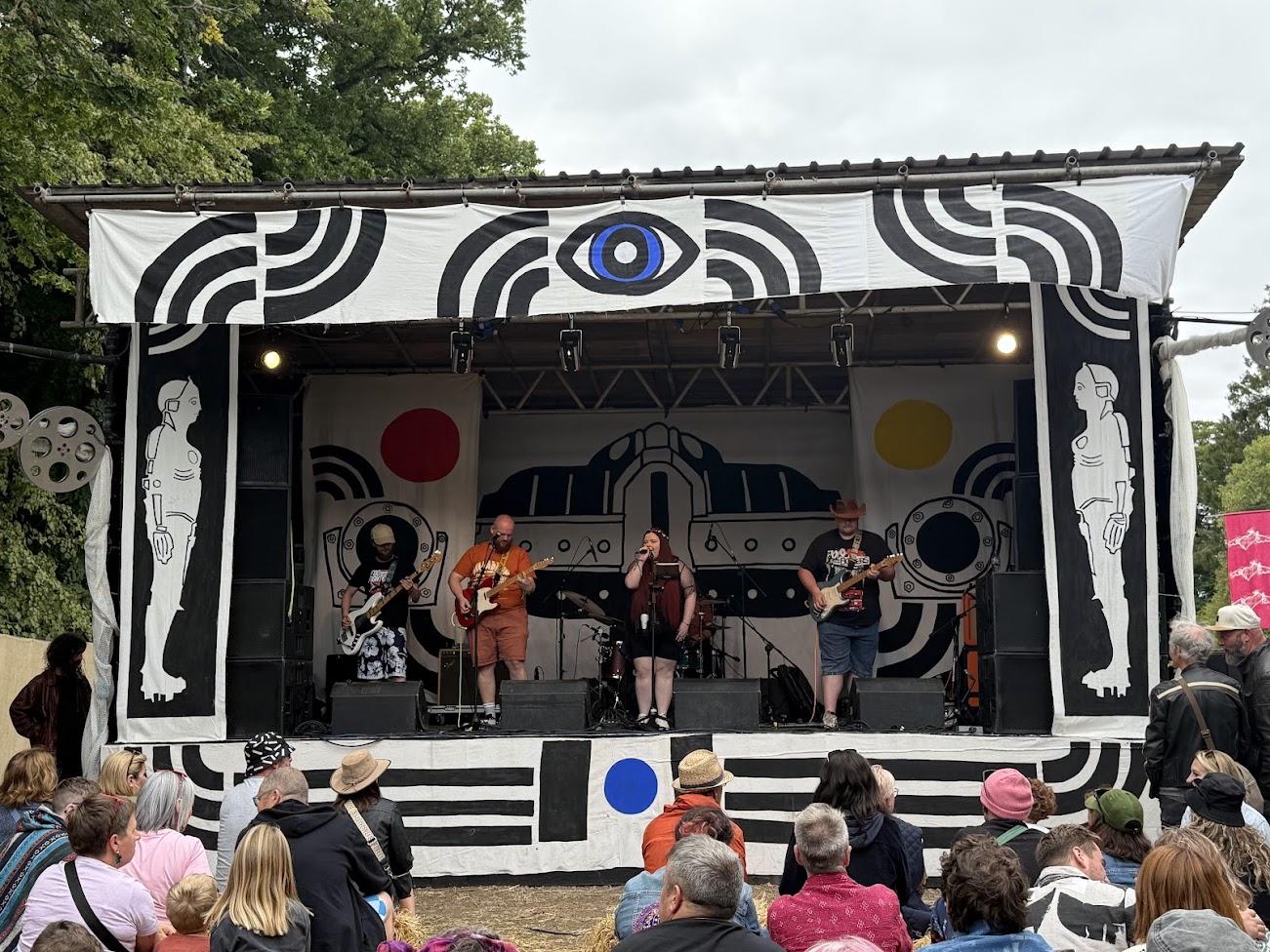 Haggis, Neeps and Fatties performing on an outdoor stage, with Calvin wearing a cowboy hat on the right